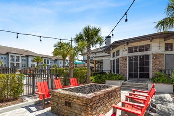 a patio with red chairs and a tree in front of a building at The Loree, Jacksonville, 32256